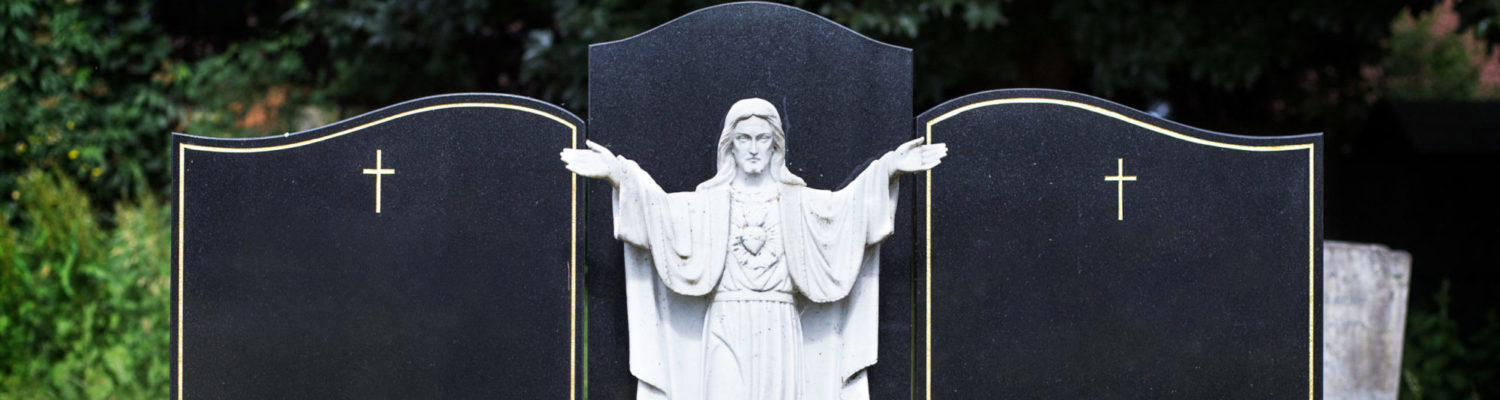 Blank elaborate gravestones with jesus figure in between and flowers at base. Beautiful marble double headstones.